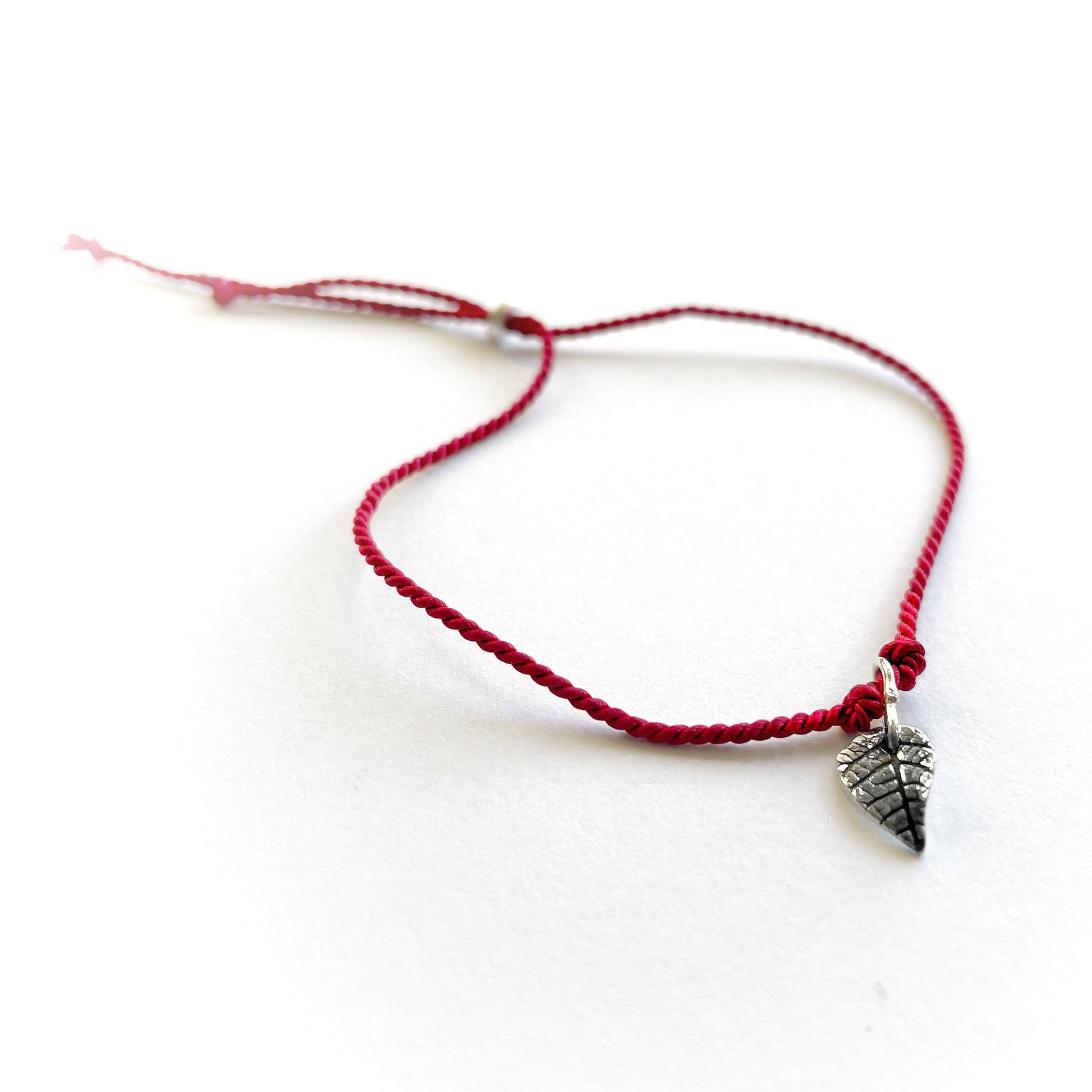 Handmade red silk string bracelet with silver leaf charm, crafted in Ireland, symbol of luck and love
Handmade red silk bracelet with silver bird charm, artisanal Irish jewellery